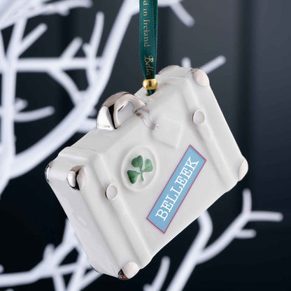Belleek Vintage Suitcase Ornament - A White ceramic suitcase hanging ornament with Belleek label  and green shamrock on a dark background.