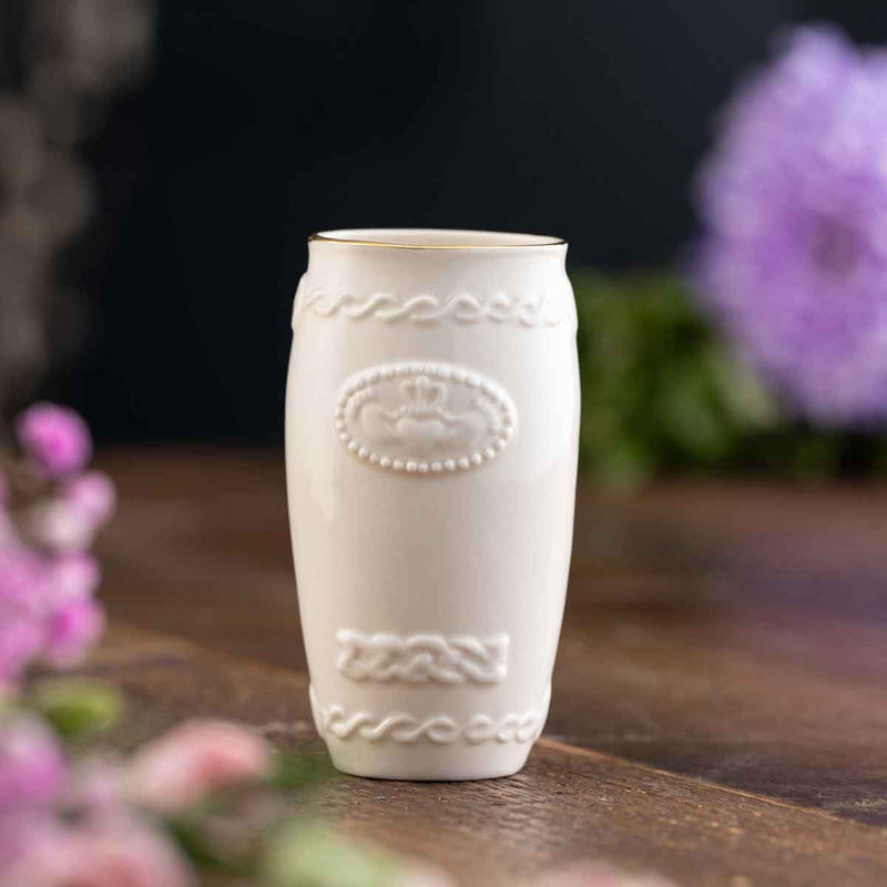 Belleek PotteryCladdagh Mini Irish Vase a wooden surface with blurred flowers in the background