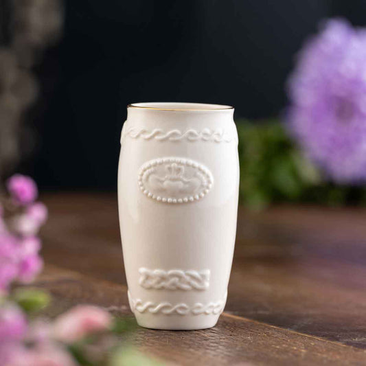 Belleek Pottery Claddagh Spill Irish Vase on a wooden surface with blurred flowers in the background