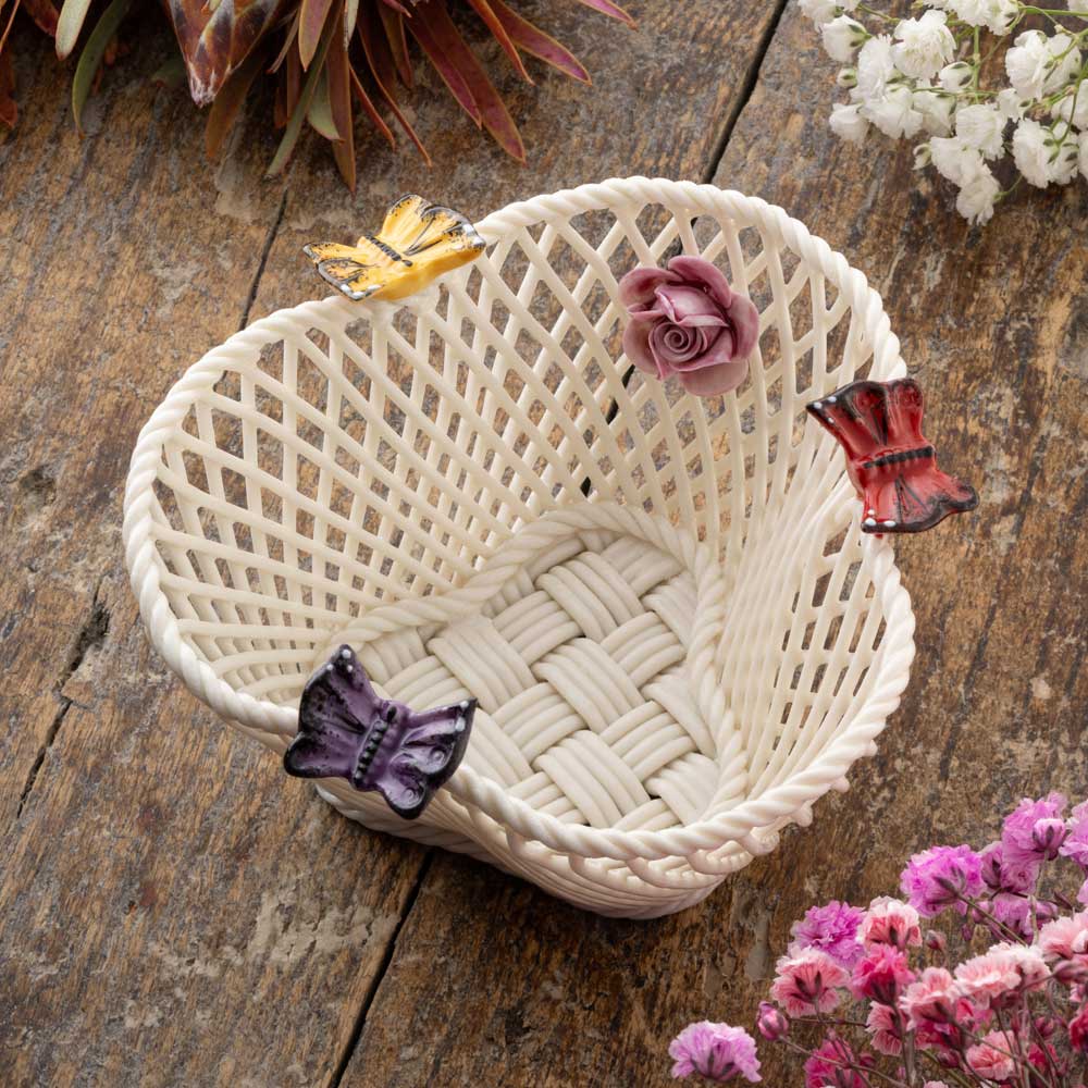 belleek pottery bright butterfly irish basket  decorated with hand painted butterflies and flowers on a wooden surface