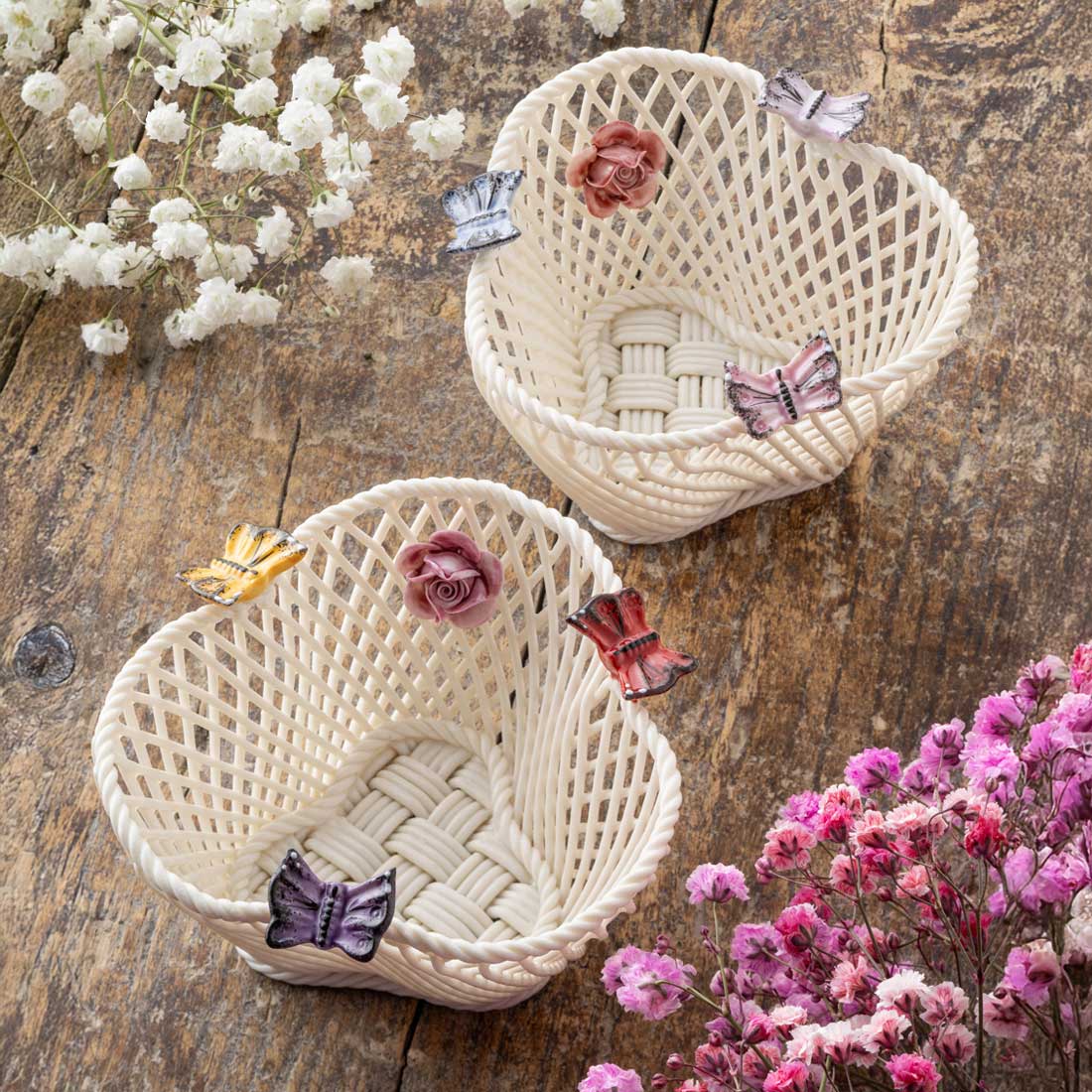 belleek pottery bright butterfly and pastel butterfly irish baskets decorated with hand painted butterflies and flowers, side-by-side on a wooden surface