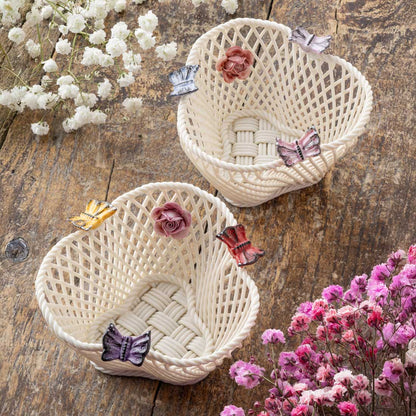 Belleek Pottery Bright Butterfly and Pastel Butterfly Irish Baskets decorated with hand painted butterflies and flowers, side-by-side on a wooden surface