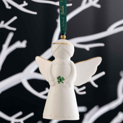 Irish Christmas | Belleek Pottery Angel Hanging Ornament set against a black background with white branch silhouettes.