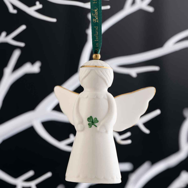 Irish Christmas | Belleek Pottery Angel Hanging Ornament set against a black background with white branch silhouettes.