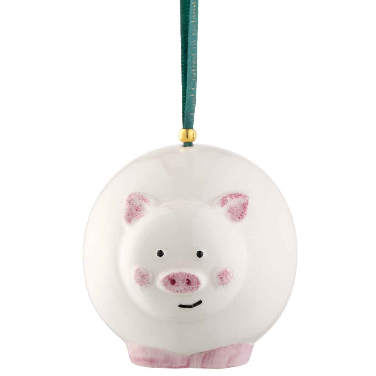 irish christmas | belleek pottery pig hanging ornament suspended by a dark green ribbon with a gold connector on a white background.