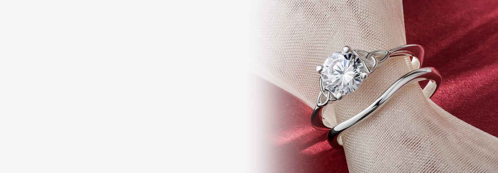 White Gold Diamond Irish Trinity Knot Wedding Ring and matching wishbone band on a red background