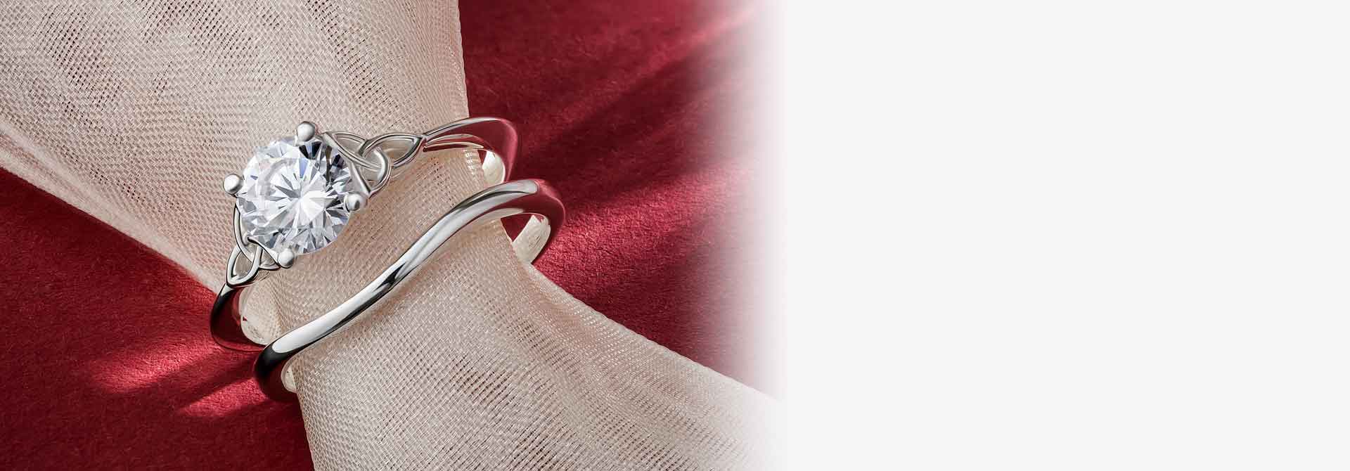 White Gold Diamond Irish Trinity Knot Wedding Ring and matching wishbone band on a red backgroundWhite Gold Diamond Irish Trinity Knot Wedding Ring and matching wishbone band on a red background