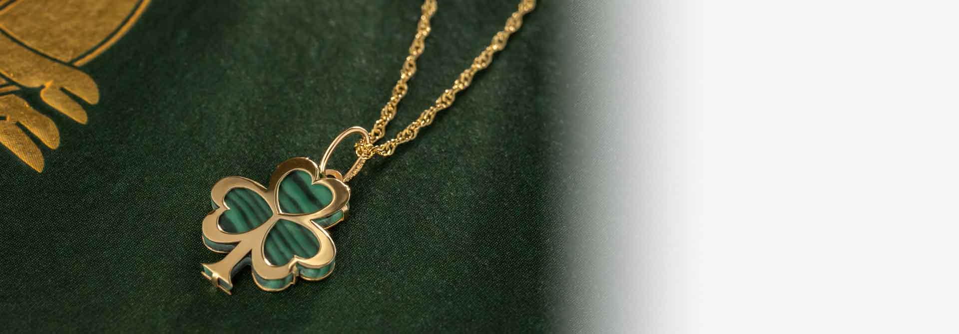 10k Gold Malachite Shamrock Pendant on a dark green background with gold Celtic design