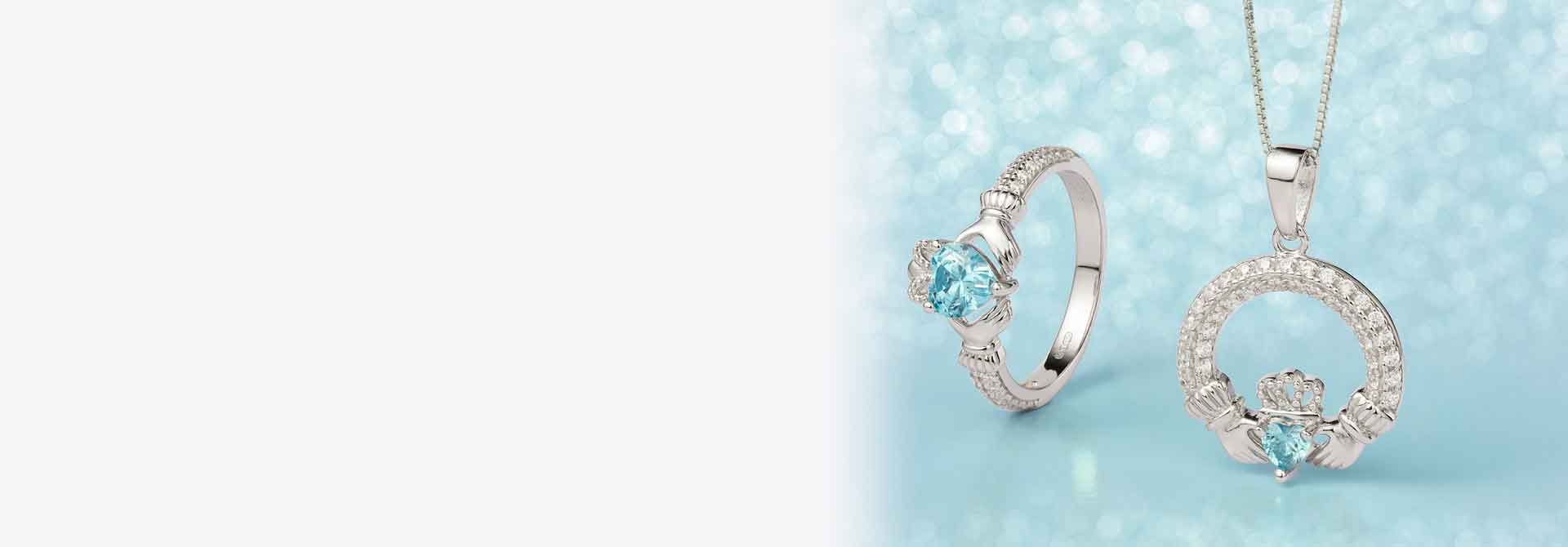 Sterling Silver Crystal Birthstone Claddagh Ring and Necklace with March's Gemstone Aquamarine against a light blue backdrop
