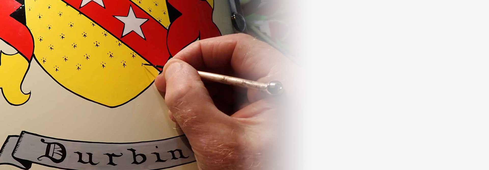 Hand painting a coat of arms gift with a star on a red background, with 'Durbin' below.