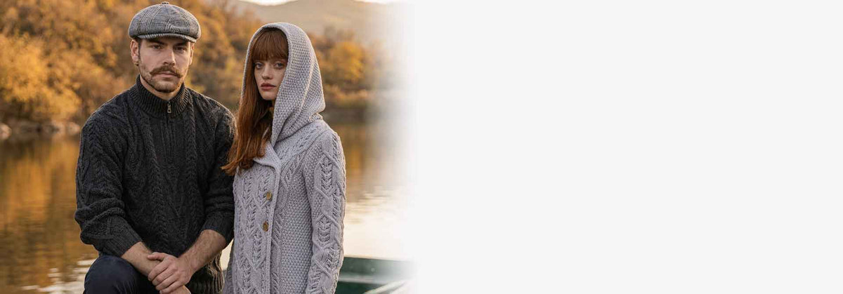 A man and a woman wearing Irish Knitwear standing in front of a lake with an autumnal backdrop