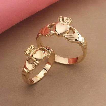 Men's  & Women's 14k Gold Puffed Heart Claddagh Ring on a brown and pink background