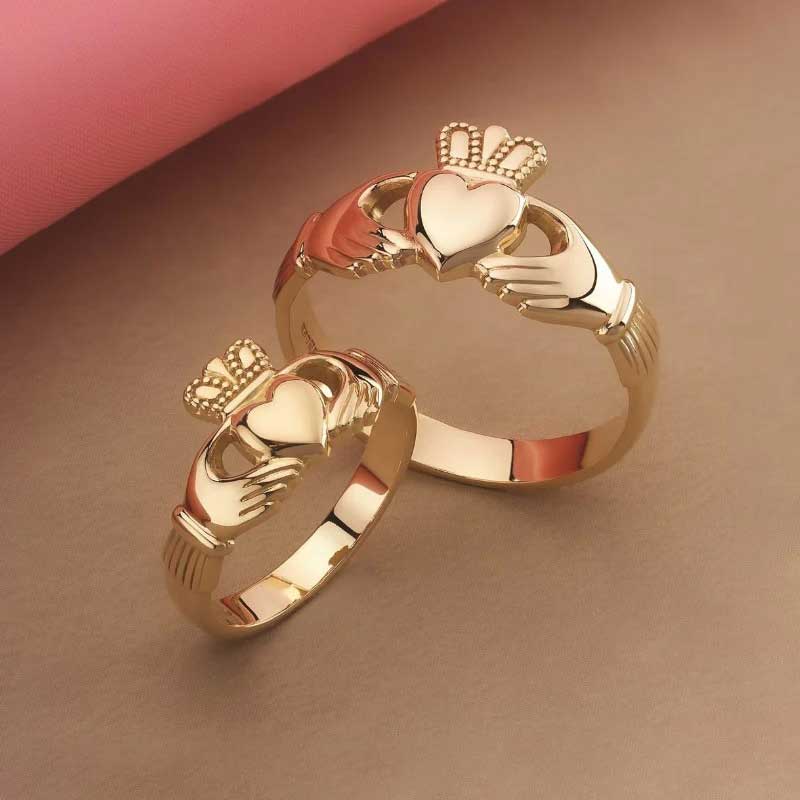 Men's  & Women's 14k Gold Puffed Heart Claddagh Ring on a brown and pink background