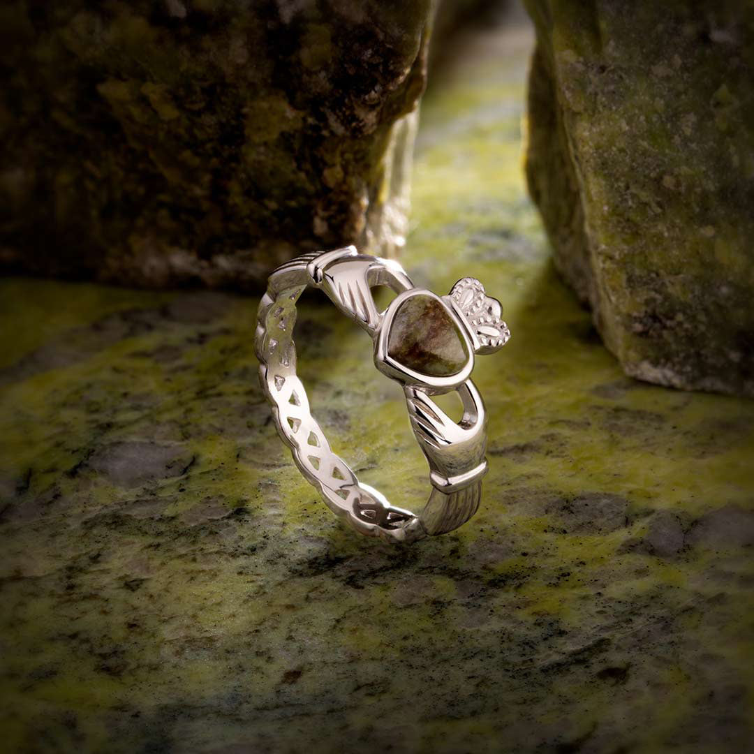 sterling silver cladagh ring with connemara marble heart and celtic weave band in sunlight on a piece of green marble
