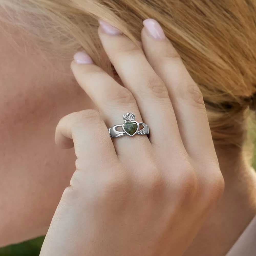 blonde woman displaying a sterling silver claddagh ring with connemara marble heart on her left hand