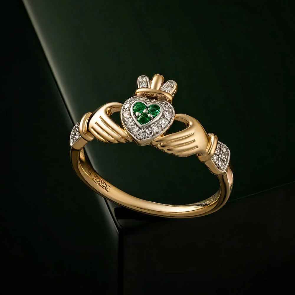 ladies 14k gold emerald and diamond encrusted claddagh ring on a dark green background