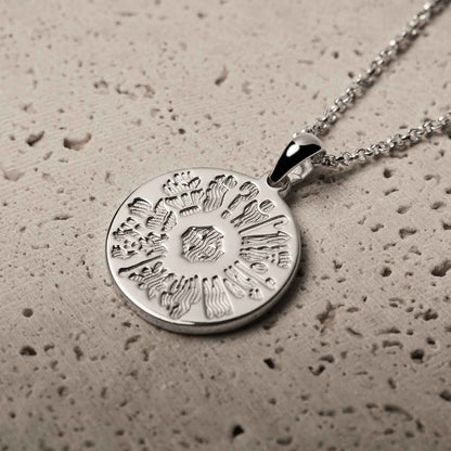 History of Ireland Sterling Silver Disc Irish Pendant on a textured beige surface