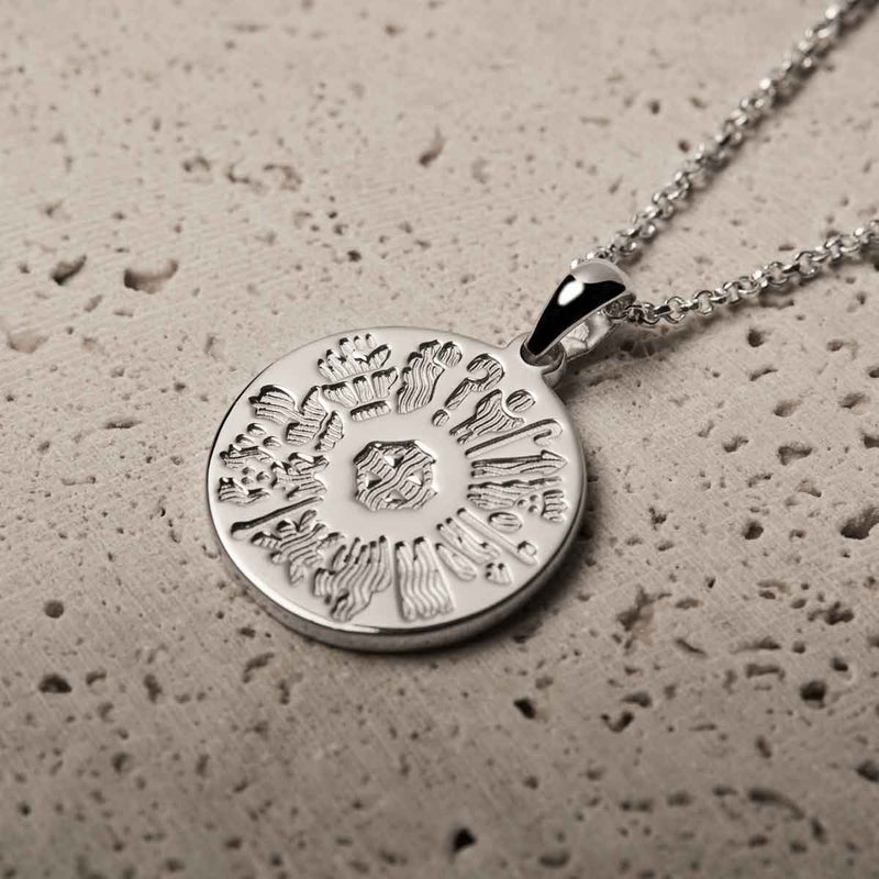 History of Ireland Sterling Silver Disc Irish Pendant on a textured beige surface