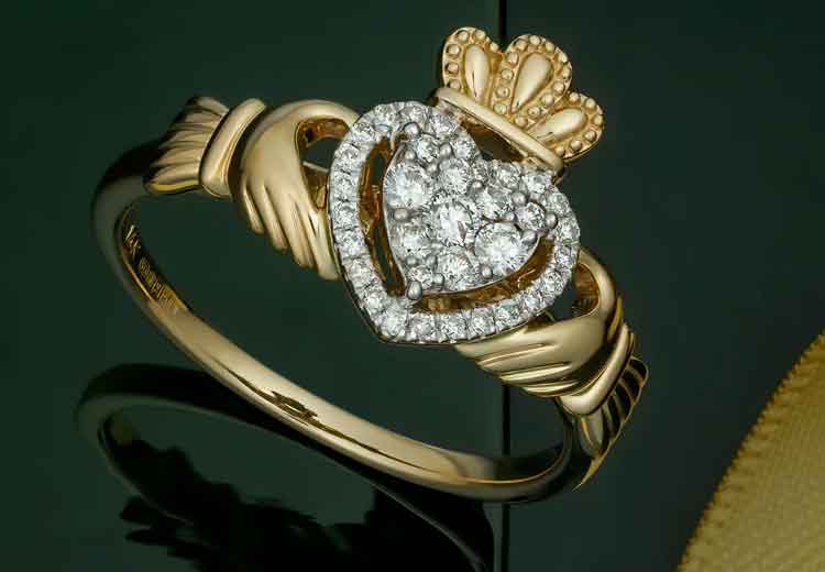 14k Yellow Gold Diamond Heart Ladies Claddagh Ring on a dark green surface
