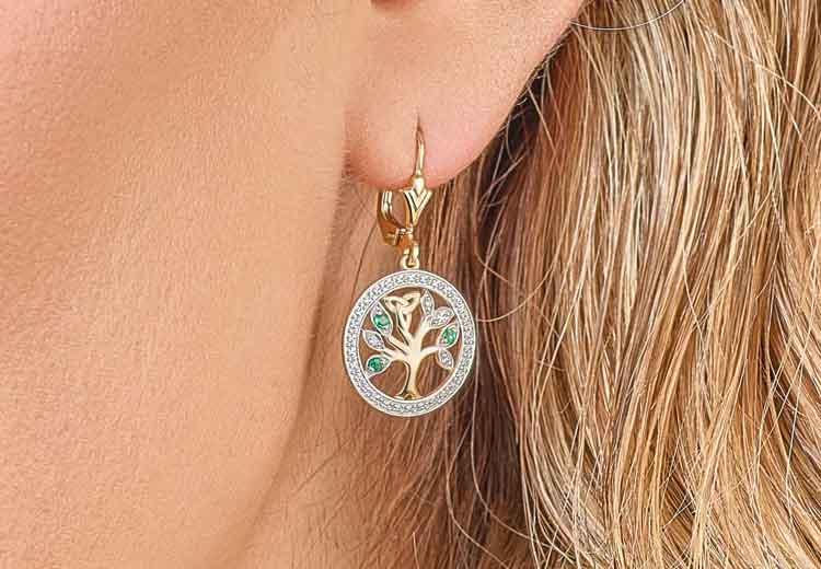 14k Gold Celtic Tree of LIfe Earring with emeralds and diamonds worn by a person with blonde hair 