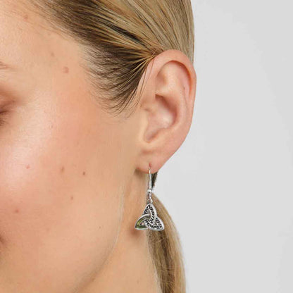 A pair of Sterling Silver Connemara Marble Accent Celtic Trinity Knot Earrings by a woman with blonde hair on a plain background