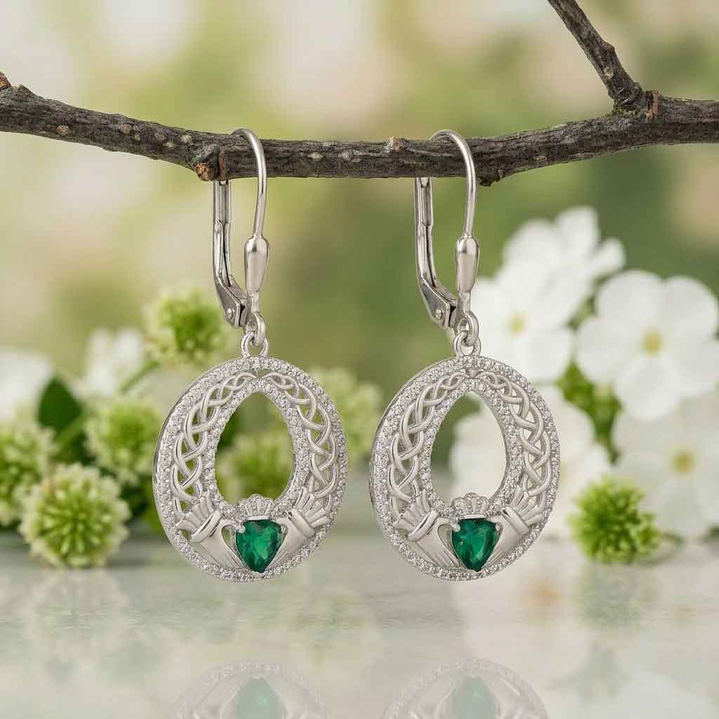 sterling silver celtic green heart claddagh earrings hanging on a branch with flowers in the background