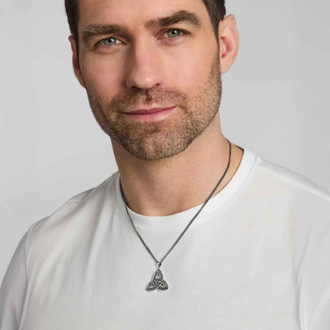 man wearing a white shirt modelling a sterling silver connemara marble accent celtic trinity knot pendant against a light gray background