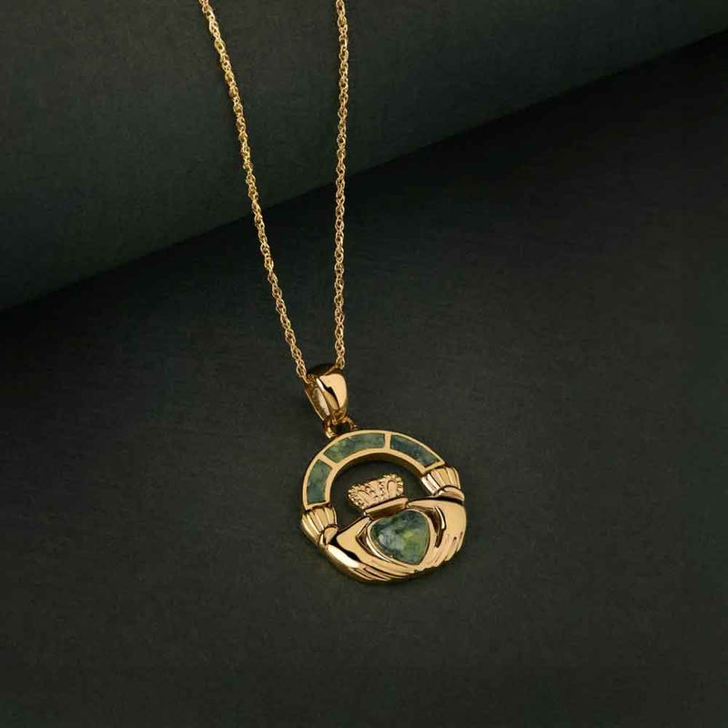 Irish Necklace - a 14k Gold Connemara Marble Claddagh Pendant against a dark green fabric background