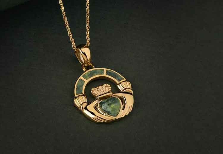 Gold claddagh pendant with Connemara Marble heart on a dark background
