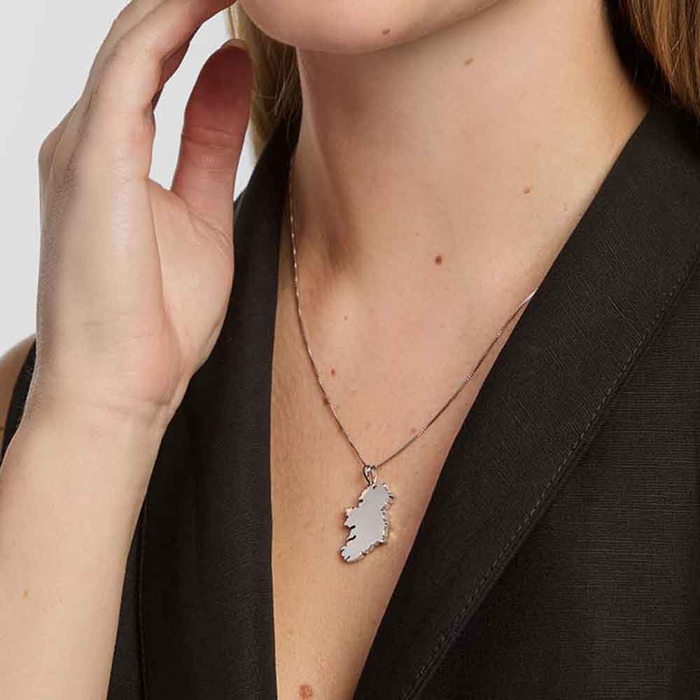 woman wearing a  sterling silver large map of ireland pendant, set against a neutral background