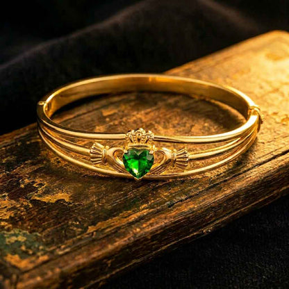 Irish Bangle | Gold Plated Green Crystal Heart Claddagh Bangle on an old wooden surface