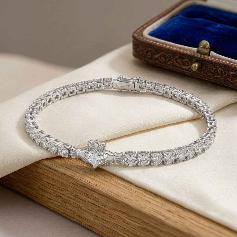 Sterling Silver Crystal Claddagh Tennis Bangle on a wooden surface with an antique jewelry box in the background.