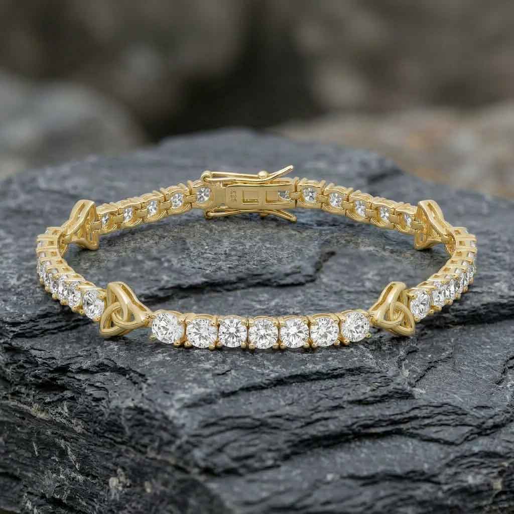 gold plated sterling silver crystal trinity knot tennis bracelet on a dark stone surface