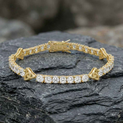 Gold Plated Sterling Silver Crystal Trinity Knot Tennis Bracelet on a dark stone surface