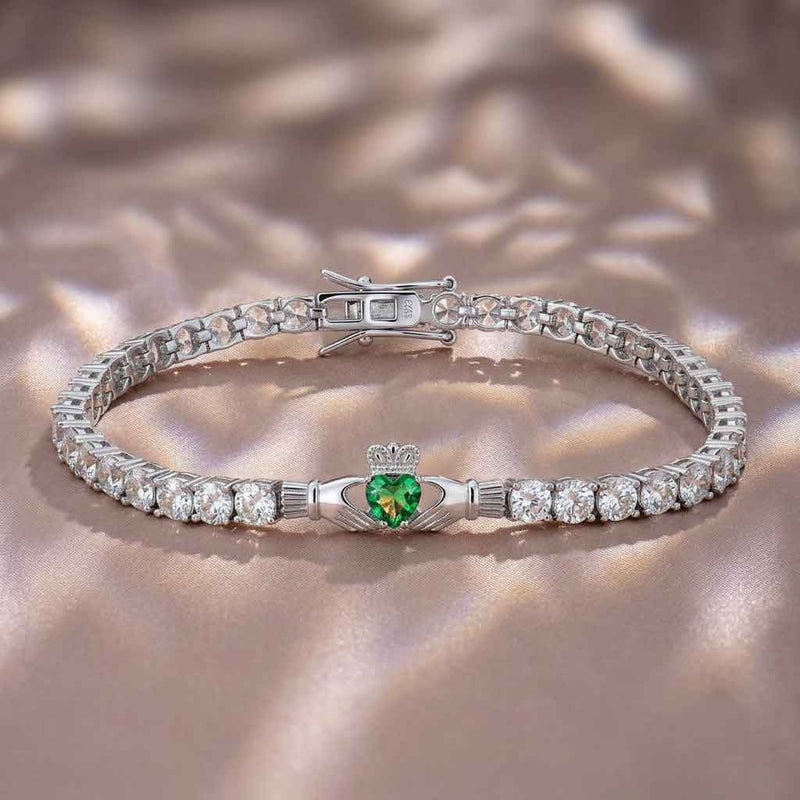 Sterling Silver Green Crystal Heart Claddagh Tennis Bracelet on a textured surface.