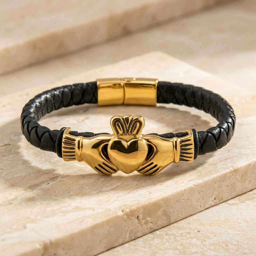 gold plated leather mens claddagh bracelet on a white background on a light stone surface