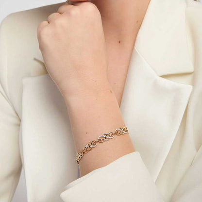 A close-up of a woman wearing an Irish 14k Gold Diamond Celtic Knot Bracelet, styled with a cream-colored blazer.