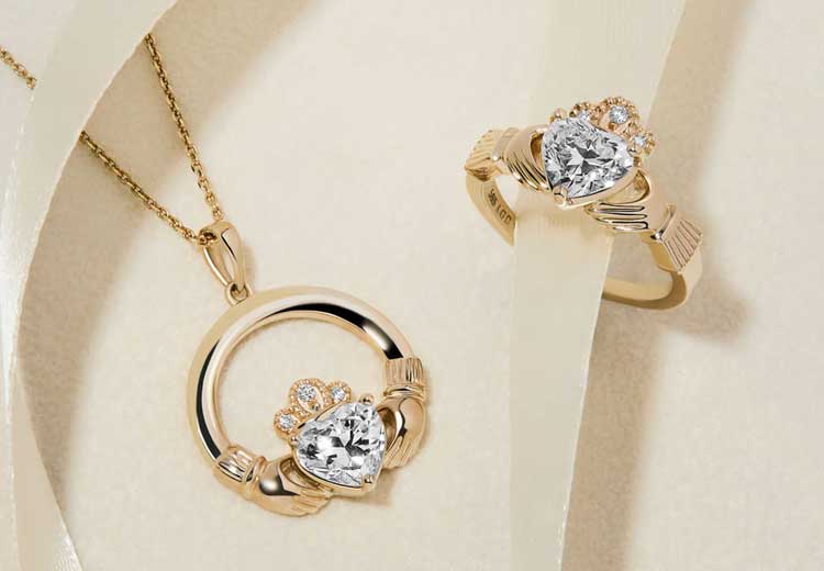 14k Gold Diamond Claddagh Necklace & Claddagh Ring on a beige background.