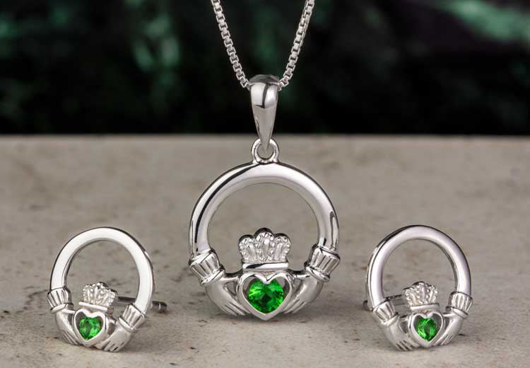 Silver Claddagh Necklace and Earings with a green crystal heart on a grey surface with green marble background